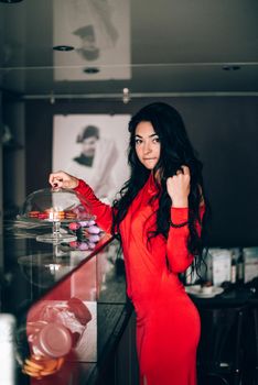 sexy woman in a red dress with black hair in a confectionery. Long black hair. obsession with red. Selective focus, film grain