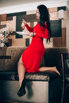 sexy woman in a red dress with black hair eats a croissant. temptation with food. attractive legs. obsession with red. Selective focus