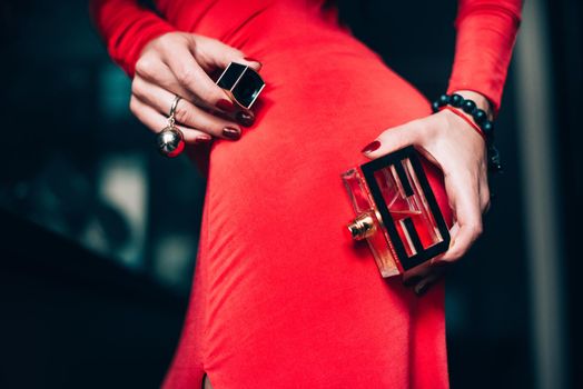 Charming young woman in red sexy dress posing. Sensual gorgeous young woman hold parfume in hands. obsession with red. Selective focus, filmgrain