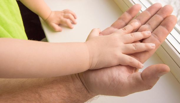 The child's hand rests on the palm of an adult male, child protection.