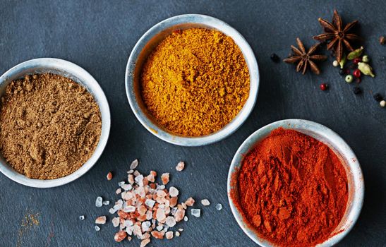 Cropped shot of an assortment of colorful spices in bowls.