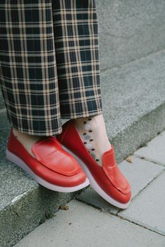 woman's legs in chequered trousers and red shoes.