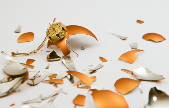 Broken golden ornament laying on a white background