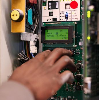 Cropped shot of an unidentifiable man pressing a button on an electrical panel.