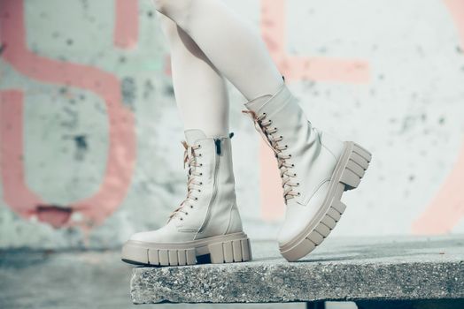 Female legs wearing white fashion boots with laces.