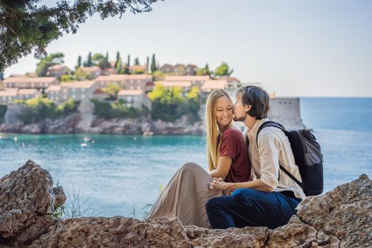 Man and woman tourists on background of beautiful view of the island of St. Stephen, Sveti Stefan on the Budva Riviera, Budva, Montenegro. Travel to Montenegro concept.