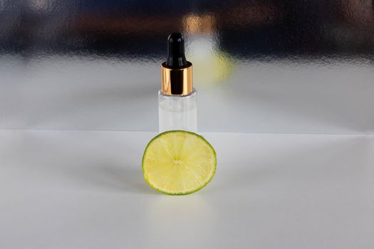 A piece of lime and a frosted bottle with an eyedropper, highlighted on a glossy background. The layout is suitable for cosmetics design