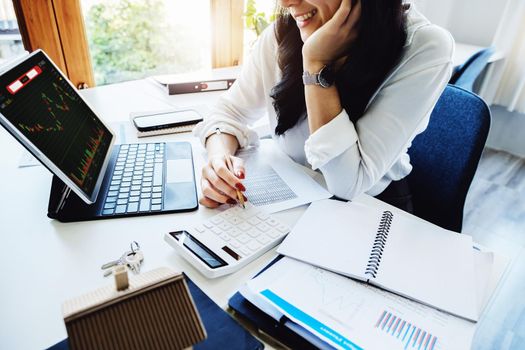 Stocks, Financial Statements and Investments , A smiling Asian woman with joy holds a pen and uses a stock market return calculator for her company