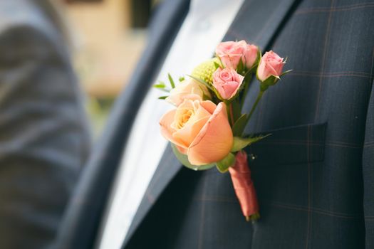 Close up image of beautiful boutonniere on the groom's jacket. Soft focus on boutonniere.