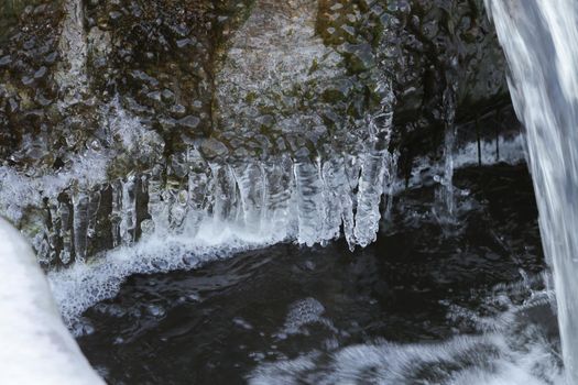 Flowing water close-up and icicles with ice.