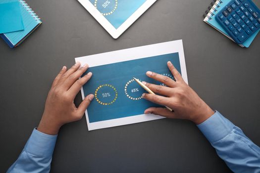 man hand with pen analyzing bar chart on paper.