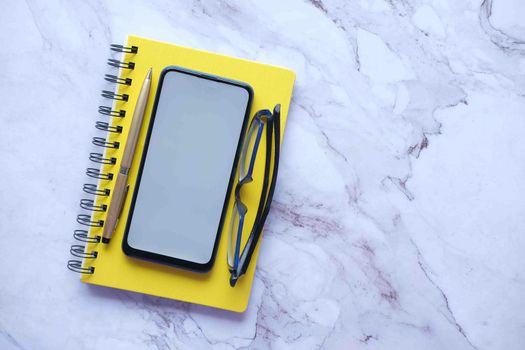 top view of smart phone and notepad on table .