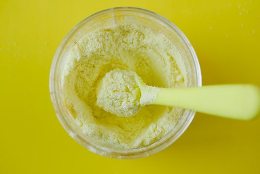 baby milk powder and spoon on yellow background .