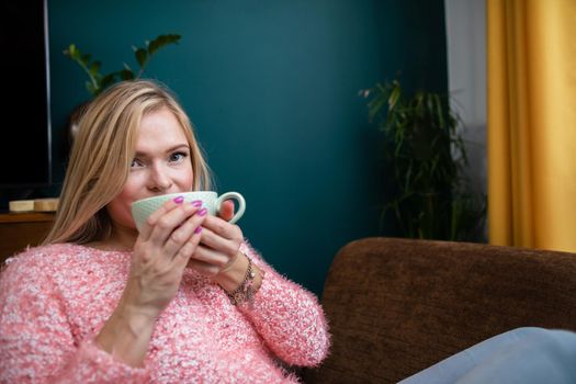 A relaxed girl enjoys an aromatic cup full of hot coffee.