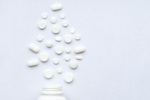 Flat lay composition with bunch of different colorful pills scattered on table from popped plastic bottle.