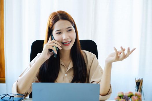 A female business woman is using the telephone to communicate with colleagues for financial planning and investment planning