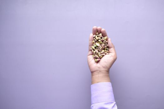top view of natural pistachios nut on hand against purple background ,