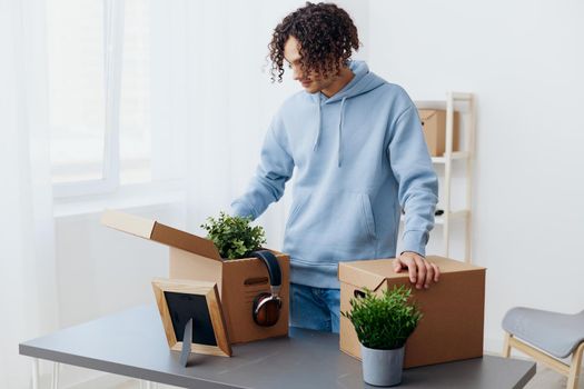 guy with curly hair unpacking things from boxes in the room interior. High quality photo