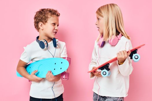 Stylish little boy and cute girl skateboards in the hands of entertainment isolated background. High quality photo