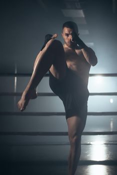 Muscular MMA fighter practicing kick, fight club concept. High quality photo