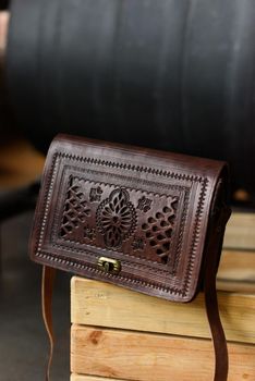 small brown women's leather bag with a carved pattern. indoor photo