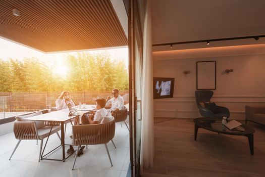 An elderly couple enjoys the terrace of a luxury house with their son during the holidays. Selective focus. High-quality photo