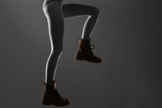 Sexy female legs with white leggings and waterproof boots. Side lit half silhouette.