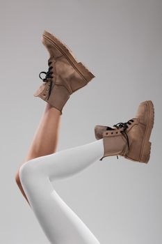 Sexy female legs wearing boots. One leg with white leggings.