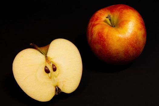 Ripe red apples on a dark background, whole apple and cut in half
