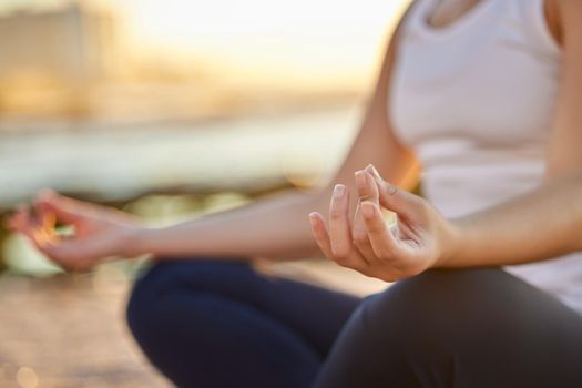 Cropped shot of an unrecognizable young woman meditating on the beach.