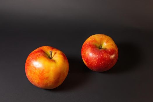 Two ripe whole red apples on a dark background