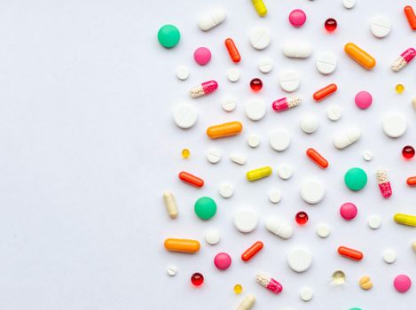 Creative layout of colorful pills and capsules on green background. Minimal medical concept.