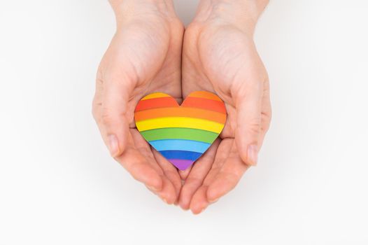 Female hands with rainbow paper heart isolated on white background