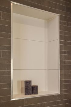 Recess in the wall with two scented candles tiled in a modern bathroom