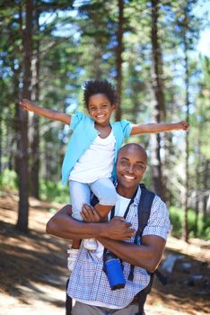 A happy young african father playing with his daughter while outdoors in nature.