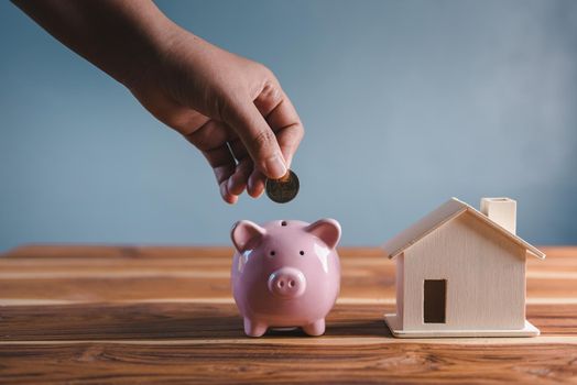 Money Savings for Future Property House Concept, Hand is Putting Coin Into Piggy Bank for Saving Future Housing Real Estate Ownership. Banking Fund for Investing House Asset and Real Estate