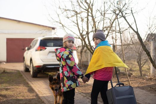 Ukraine military migration. two little girls with a suitcase. Flag of Ukraine, help. Crisis, military conflict.