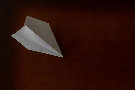 White paper plane on brown background, travel and holiday concept