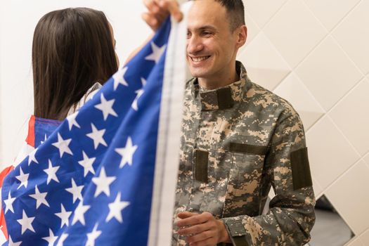 Soldier with flag of USA and his little daughter hugging, space for text.