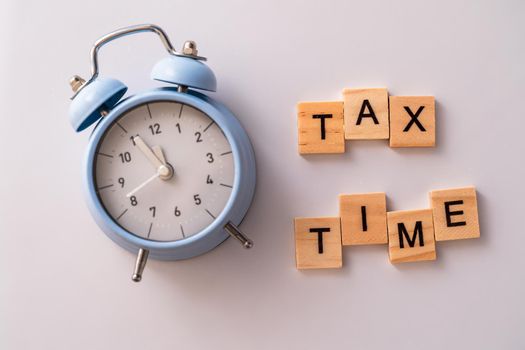 Close-up of alarm clock next to tax time concept on chalkboard.