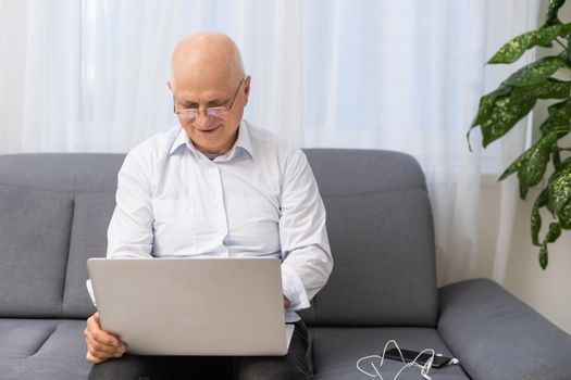 Happy old caucasian businessman smiling working online watching webinar podcast on laptop and learning education course conference calling make notes sit, elearning concept.