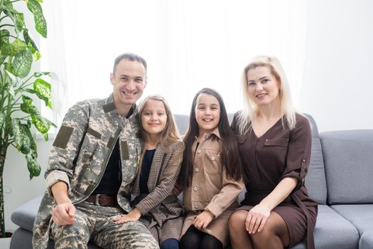 Soldier in camouflage and his family sitting at home.