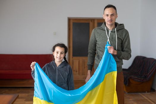 Father with daughter holding Ukrainian flag. Peace and pray for Ukraine.