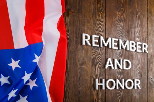 words remember and honor laid with silver metal letters on wooden background with USA flag on the left side in linear perspective