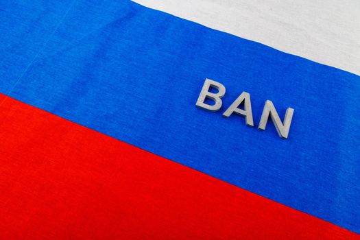 the word ban laid with silver metal letters over fabric tricolor flag of the Russian Federation