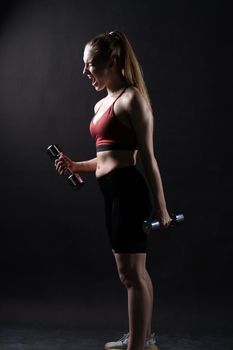 Stands beautiful A on with black background a dumbbells girl Keira Knightley girl dumbbells fitness body, In the afternoon female lifestyle from exercise from trainer dumbbell, sportswear biceps.