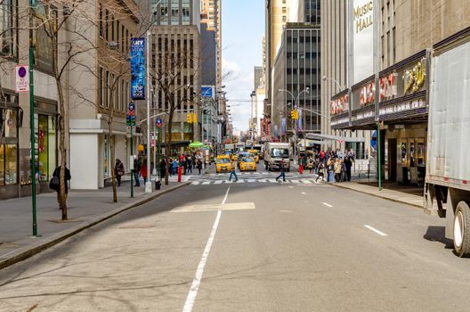 New York City Street next to Radio City Music Hall with traffic, yellow Taxi Cabs and cars, on the horizon behind two crosswalks during daytime, horizontal