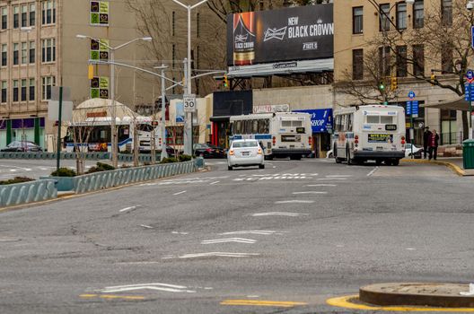 Staten Island, New York City, Buses and cars leaving the Ferry Terminal Station, rear view, during winter day retail stores and advertisement in the background, horizontal