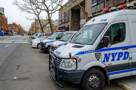 NYPD Different New York Police Department cars, trucks and vans parked next to each other at the street at a police station, Harlem, New York City, during winter day with overcast, horizontal