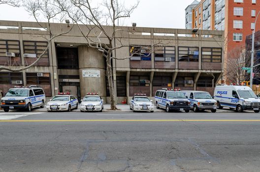 NYPD Different New York Police Department cars and trucks and van parked next to each other at a police station in Harlem next to the street, New York City, during winter day, horizontal